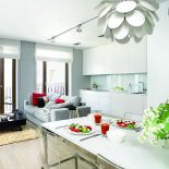 Szafki kuchenne zrobione na zamówienie z lakierowanego MDF-u. Sofa marki Dublo, dywan, szare poduchy i koc - Belbazaar.