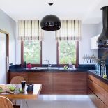 Szafki w orzechu amerykańskim, nowoczesny okap i lampa Fly Kartell.