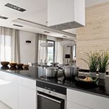 Szafki z lakierowanego na biało mdf-u, przykryte czarnym granitowym blatem, takim samym jak stół, zostały