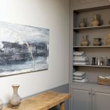 Szare meble zostały połaczone z dodatkami z naturalnego, starego drewna.