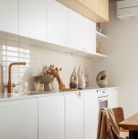 biała kuchnia z drewnem w eleganckim apartamencie