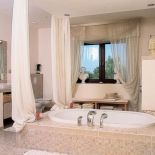 Ta łazienka wygląda jak salon. Wannę otaczają woale, które udają kolumny.