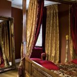 Ta sypialnia utrzymana jest w eleganckich, ciemnych kolorach - czerwienie i brązy z dodatkiem złota.