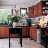 Także w kuchni panuje mieszanina stylów - rustykalne drewniane szafki, industrialny aluminiowy kubeł na śmieci