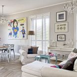 Tłem dla sztuki są białe ściany i jasne meble.