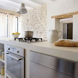 Trzymetrowa wyspa jest zrobiona z betonu - surowy materiał świetnie pasuje do kamiennej ściany.