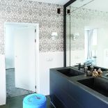 Urządziły ją płytki z falistym wzorem i umywalka ze szczotkowanego granitu Indian Black Dark. Tapeta z Magic Home.