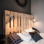 Uwagę zwraca pomysłowe łóżko, którego stelaż i bezgłowie wykonane zostały z odpowiednio przygotowanych palet drewnianych.