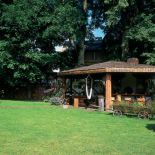 W cieniu wysokich drzew, pośród kwiatów - to idealne miejsce na przyjęcia w ogrodzie.