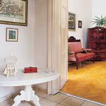 W holu stoi mały biały stoliczek. Włoska uroda