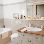 W jasnej łazience akcentem jest drewniany blat.