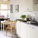 W kuchni drewniany stół z białymi nogami.