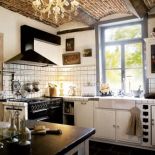 W kuchni wenecki żyrandol na tle ceglanego sufitu, superpiecyk La Cornue i stół z bazaltowym blatem. Do tego dużo