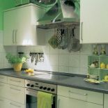 W kuchni wrażenie świeżości i przestrzeni dają proste białe szafki i chłodna zieleń ścian.