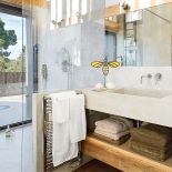 W łazience ciekawe zestawienie betonowych, szarych ścian z ciepłym drewnem, z którego wykonano półkę pod umywalką.