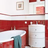 W łazience czerwień kafelków przełamana jest stylowymi białymi meblami.