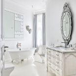 W łazience mieszają się elementy stylowe z dizajnerskimi: obok wanny na ozdobnych nóżkach przezroczysty stołek