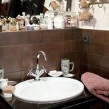 W łazience świetnie sprawdza się połączenie piaskowej ściany z brązowymi płytkami.