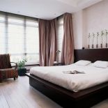 W minimalistycznej sypialni uwagę zwraca afrykańska tkanina na fotelu.