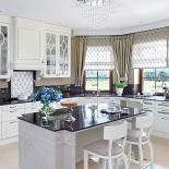 W pałacowej kuchni te same wzory co w salonie: elipsy na frontach szafek i ażurowe wstawki z błyszczacego metalu,