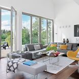 W salonbie dominują szarości (kanapy) rozweselone kolorowymi fotelami i dodatkami, np. poduszkami i pledami.