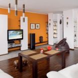 W salonie charakteru nadaje pomarańczowa ściana.