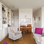 W salonie stoi duża stylizowana biblioteka, całości dopełniają dizajnerskie lampy Artemide.