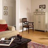 W salonie stoi jasna szafka. Dyskretny urok czerwieni