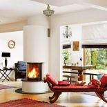 W salonie stoi szezlong z czerwonymi poduszkami.