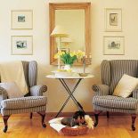 W salonie stoją fotele w szare pasy.