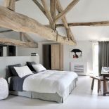 W sypialni króluje wiekowe drewno - od zjawiskowych belek pod sufitem po stolik z zydelkiem. Nawet szafkę na wysokich