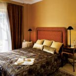 W sypialni proste meble. Głowną ozdobą są wzorzyste tkaniny, które dodają przytulności.