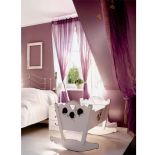 W sypialni stoi rzeźbiona biała kołyska.