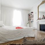 W sypialni z bielą kontrastuje złoto, ktore współgra z barwą lamparciej skóry na podłodze.