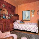 W sypialni znajdziemy zdobione drewniane meble i tkaniny w ciepłych kolorach.