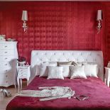 W sypialni zwraca uwagę opalizująca czerwona tapeta z wężową fakturą.