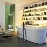 Wanna i bateria wolno stojąca zaprojektowane przez Starcka na tle komowej biblioteki. DURAVIT