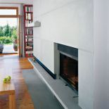 We wnętrzu, podobnie jak na elewacji, postawiono na kamień i drewno. Minimalistyczny kominek obudowano kamieniem.