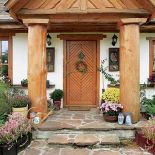 Wejście do domu tonie w kwiatach. W gościnne progi zapraszają sękate kolumny, obrazki, nawet malowane konewki.