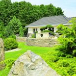 Wielkie głazy ozdabiają ogród. Zieleń, kamień i woda