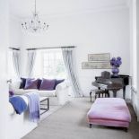 Właścicielka miała pomysł na różową sofę w kuchni, purpurowe poduszki i koce w salonie