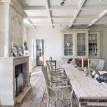 Wokół surowego stołu stoją rattanowe krzesła z Belgii i tapicerowane angielskie.