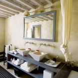 Wysmakowana łazienka. Może to zasługa powtórzeń. Błękitna rama lustra, błękitna półka, futryna. Taki sam kształt