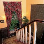 wzorzysty dywan, zasłony i kilim na ścianie - tkaniny sprawiają, że klatka schodowa też jest umeblowana .