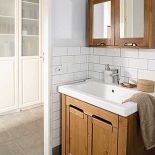 Z jasnym wystrojem łazienki kontrastują drewniane szafki.