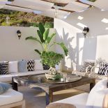 Zadaszenie górnego tarasu zrobione jest z drewnianych belek i płótna. Poduchy H M Home.