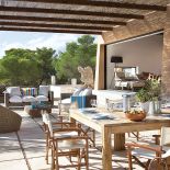 Taras z jadalnią: drewniany stół, krzesła, a obok wygodne kanapy.