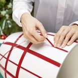 Zdejmij pasek zabezpieczający klej i delikatnie naklejaj okleinę wzdłuż wyznaczonych linii narysowanych na donicy.