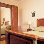 Zdobione intarsjami łoże i ogromna szafa z lustrem.