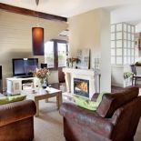 Zielone poduszki kontrastują z brązową kanapą i fotelem.